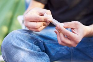 Shot of a unrecognizable person rolling a large marijuana joint.