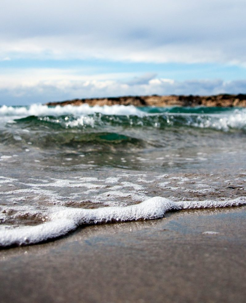 waves under white cloudy sky at daytime